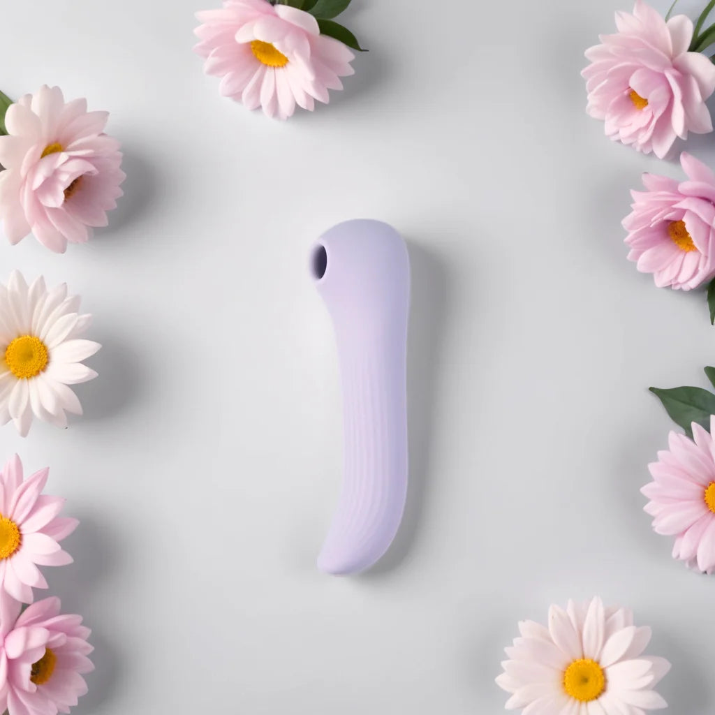 Vibromasseur lilas entouré de fleurs roses, illustrant la douceur et la double stimulation du sextoy 2-en-1 Lora de Solena, combinant aspiration et vibration