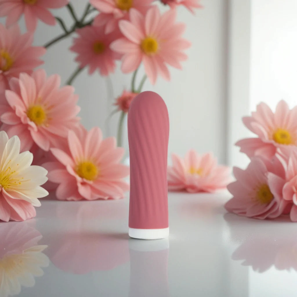 Petit vibromasseur bullet rose Mira de Solena posé sur une surface brillante, entouré de fleurs roses, illustrant un plaisir discret et toujours à portée de main