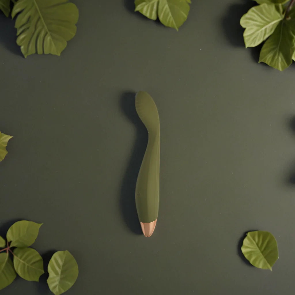 Vibromasseur vert Nova de Solena, élégant et incurvé pour la stimulation du point G, posé sur un fond végétal qui évoque la sensualité et l'harmonie avec le corps