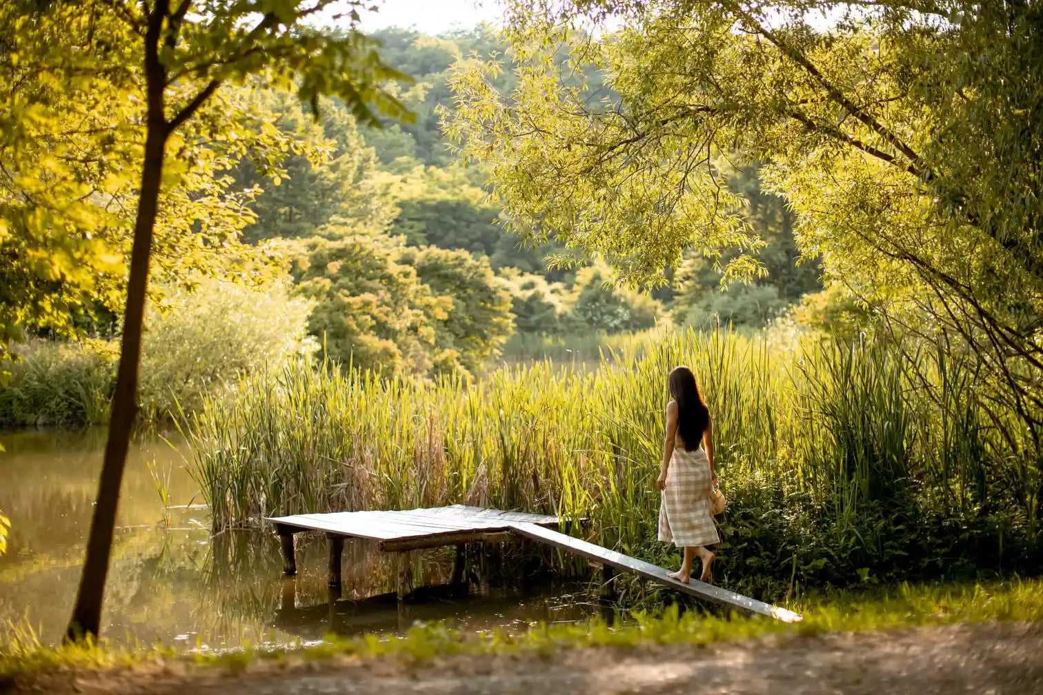 Femme marchant pieds nus sur un ponton en bois, entourée de verdure, illustrant la quête de soi et l'approche naturelle et bienveillante du concept unique de Solena