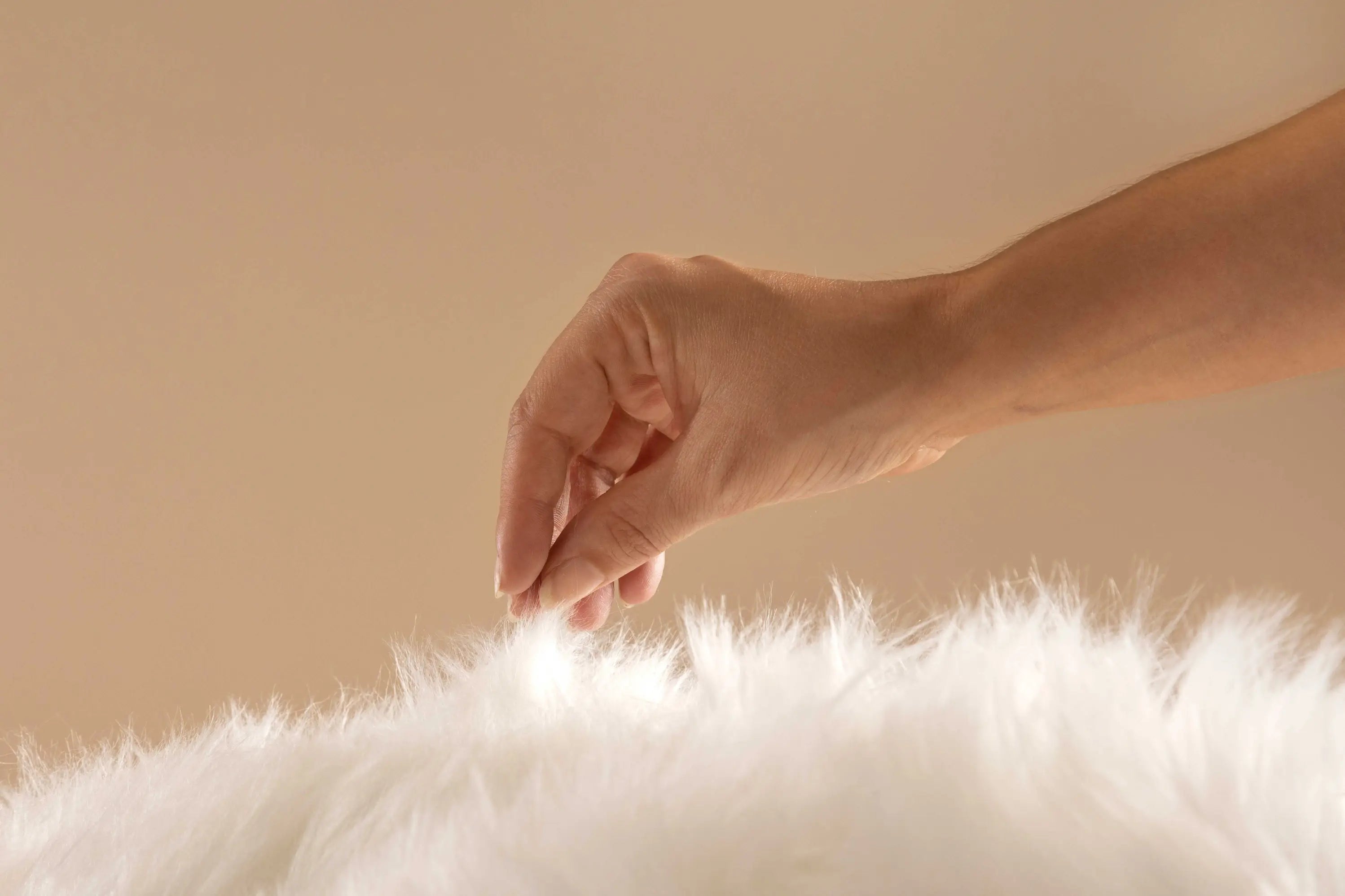 Main effleurant un tissu doux et duveteux, évoquant la sensation de confort et la facilité d’utilisation du plug anal Terra