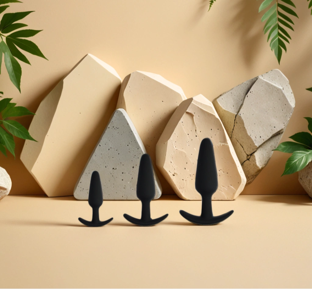 Trio de plugs anaux en silicone noir de tailles progressives, posé sur un fond minéral naturel, illustrant une exploration en douceur avec Terra de Solena