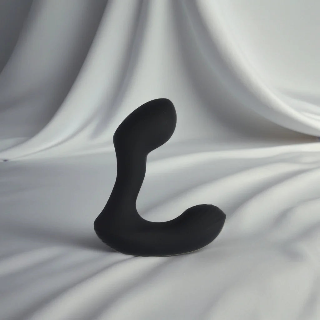Masseur de prostate noir Zoro avec télécommande, posé sur un tissu blanc soyeux, représentant un plaisir accessible à tous