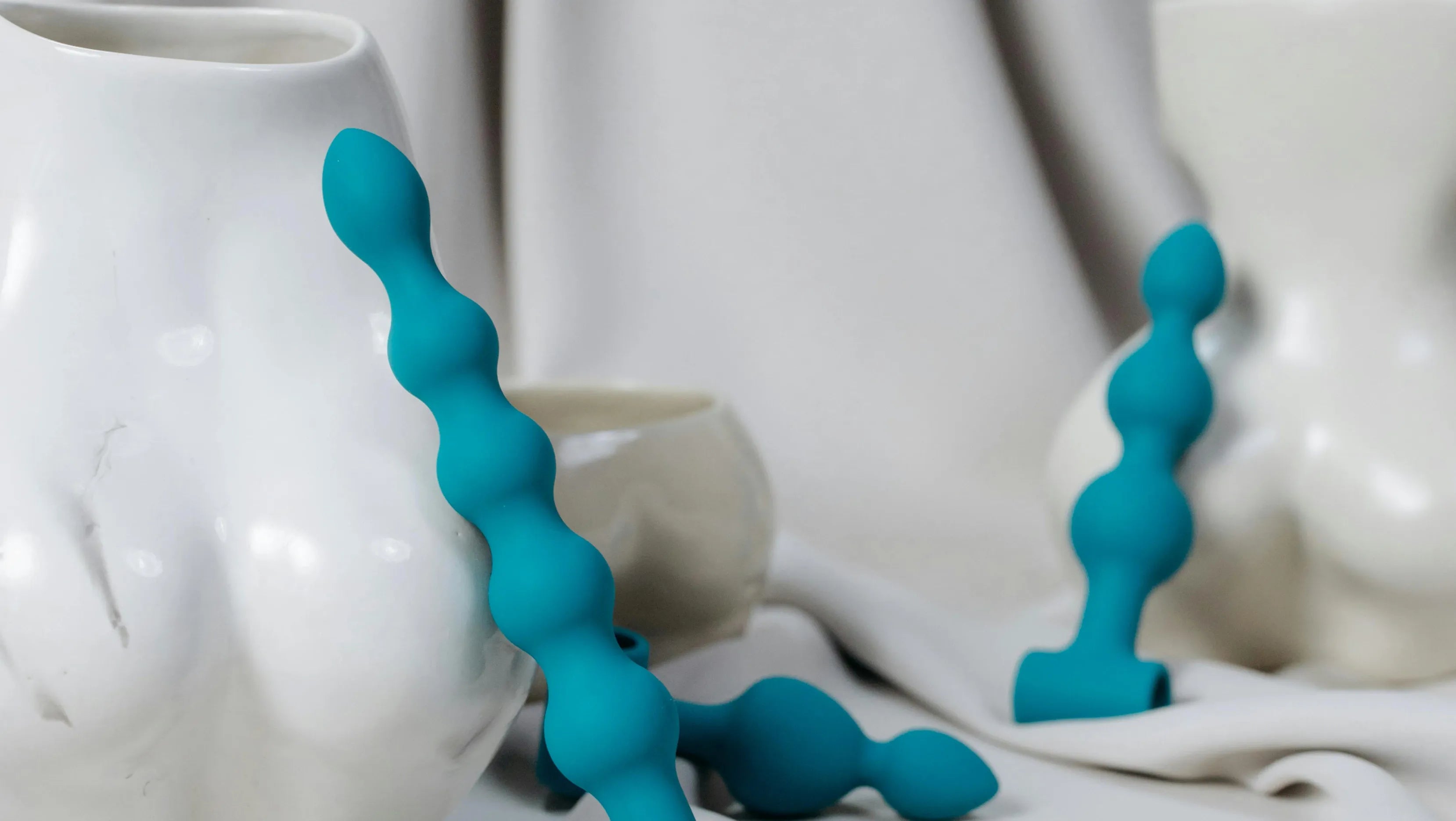 Collection de sextoys anaux en silicone turquoise, posés sur un fond doux et artistique, illustrant la diversité et l’élégance des plaisirs anaux selon Solena