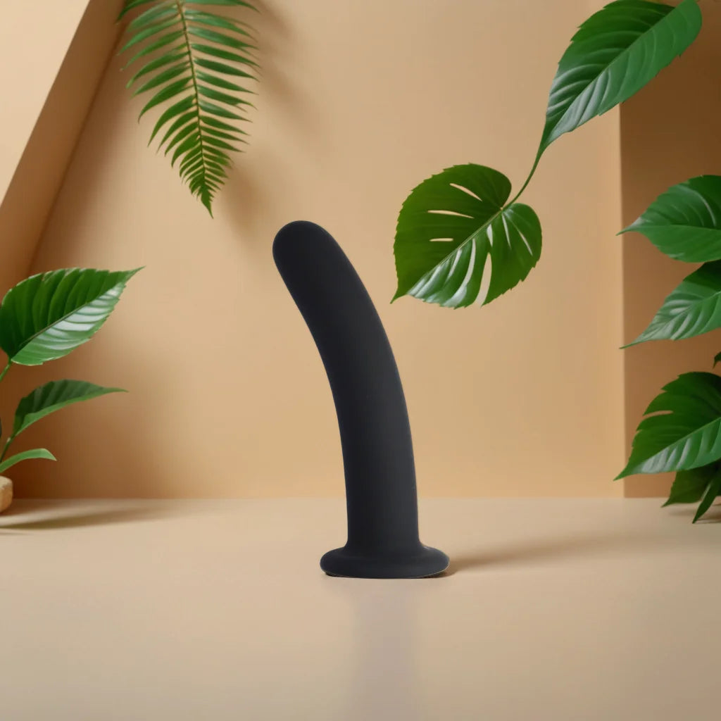 Dildo noir en silicone posé dans un décor végétal naturel, illustrant la liberté de mouvement et la stimulation intense offerte par Dora de Solena